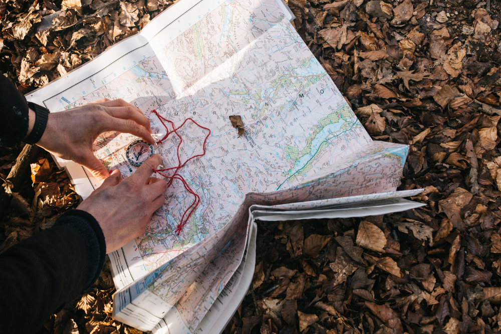 Someone taking a bearing with a compass and a paper Ordnance Survey map